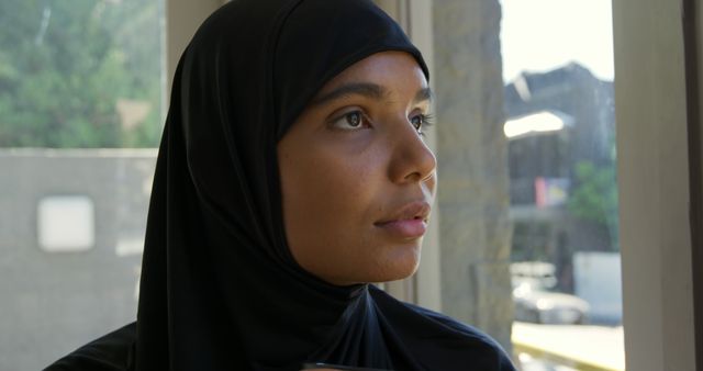 Thoughtful Woman in Hijab Looking Out Window - Download Free Stock Images Pikwizard.com