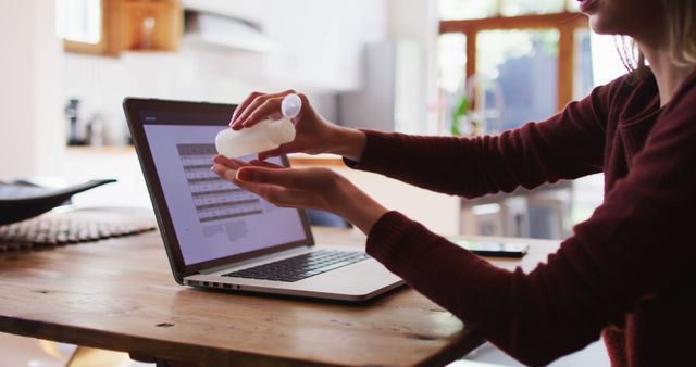 Woman Sanitizing Hands While Working on Laptop at Home - Download Free Stock Images Pikwizard.com