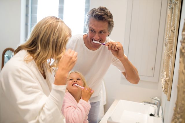 Parents and daughter brushing teeth in bathroom at home