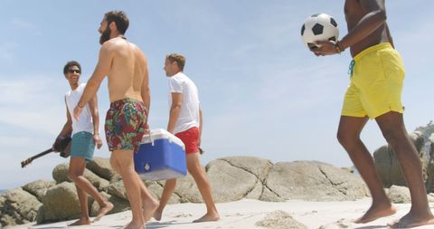 Friends Walking on Beach with Cooler and Soccer Ball on Sunny Day