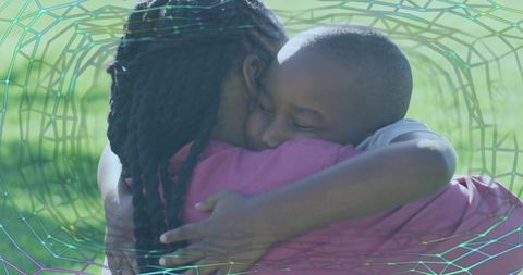 Black caregiver hugging child in sunlit park showing tender affection and comfort