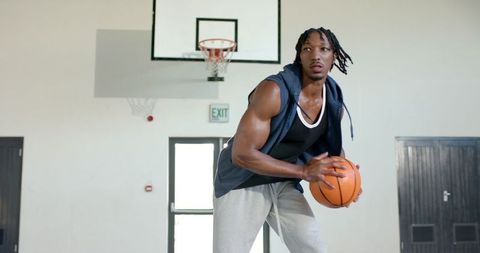 Athletic man holding basketball indoor gym concentration action