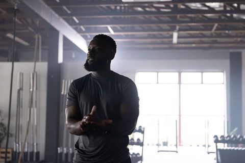 African american man preparing for strength lift in industrial gym backlit silhouette