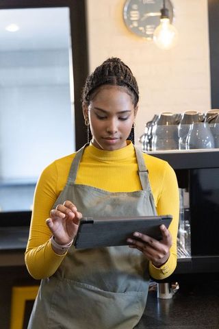 African american barista using tablet at bright specialty coffee bar
