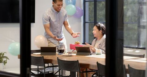 Joyful office celebration with gift giving among multiracial colleagues