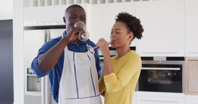 Image of happy african american couple cooking together and drinking wine. Love, relationship and spending quality time together concept.