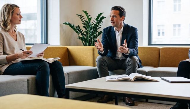 Executive leading informal team discussion in modern office lounge with natural light