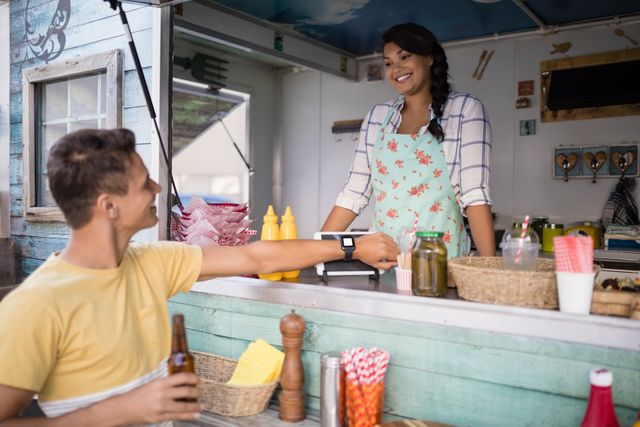 Man paying bill through smartwatch at food truck counter