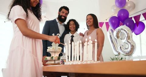 Family celebrating birthday party lighting candles together