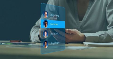 Businessman interacting with holographic contact list on smartphone at modern office desk