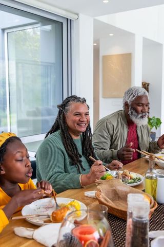 Multigenerational african american family eating together at sunlit modern dining table