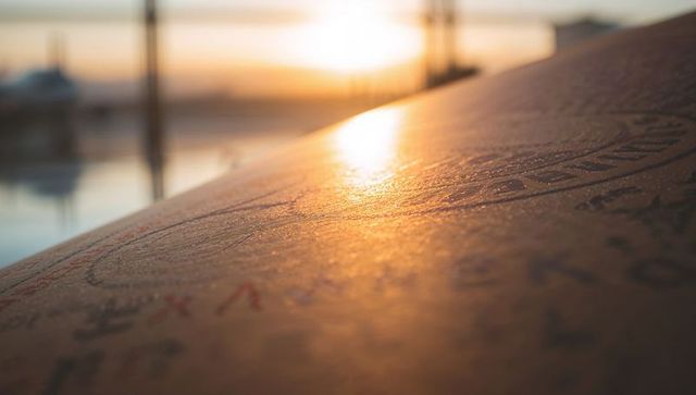 Sunlit handwritten signatures on weathered dock plank closeup at golden marina sunset