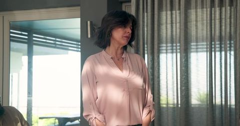 Mature Woman Standing Thoughtfully Near Window