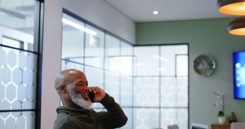 Cheerful man having a phone conversation in modern living area