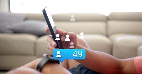 Man holding smartphone tapping notifications on couch wearing smartwatch with social badge