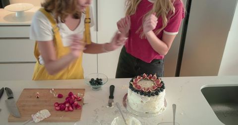 Friends Decorating Fig and Blueberry Cake in Bright Home Kitchen, Baking Together