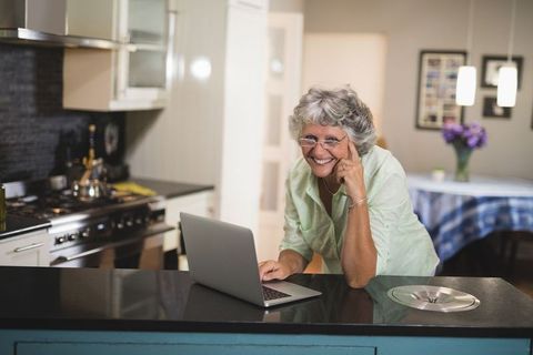 Senior Woman Using Laptop in Modern Home Kitchen