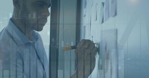 Businessman writing on glass with financial charts overlay for planning and analytics