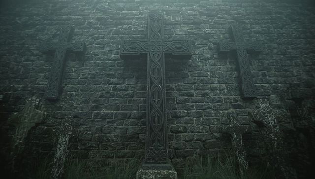 Standing ornate celtic cross showing moss and eroded gravestones by foggy stone wall