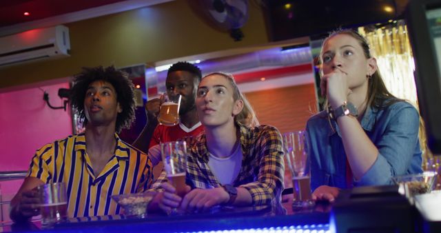 Image of diverse group of friends reacting to sports game on screen at a bar. Friendship, inclusivity, going out and socialising concept.