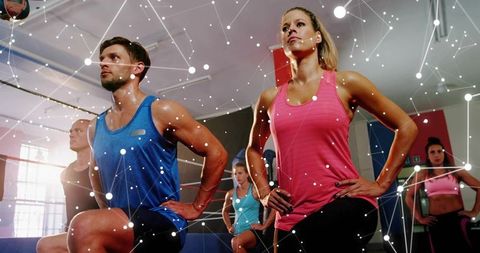 Group lunging workout featuring woman in pink tank leading energetic fitness class