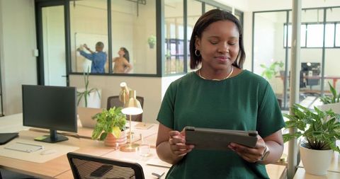 Modern office collaboration with woman using tablet and coworker using smartphone