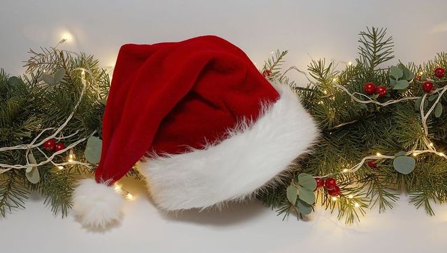 Red Santa Hat Draping Over Pine Garland with Eucalyptus, Berries and Warm Fairy Lights