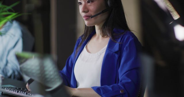 Image portrait of smiling asian businesswoman wearing phone headset, working at night in office. Business, communication, inclusivity and flexible working concept digitally generated image.