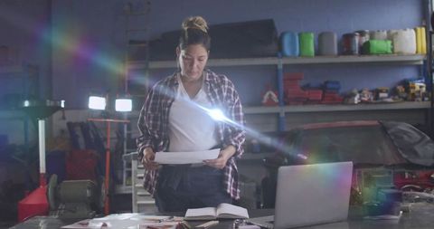 Female mechanic analyzing plans in automotive workshop