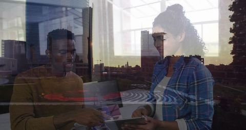 Creative team collaborating on tablet and laptop with urban skyline overlay and daylight