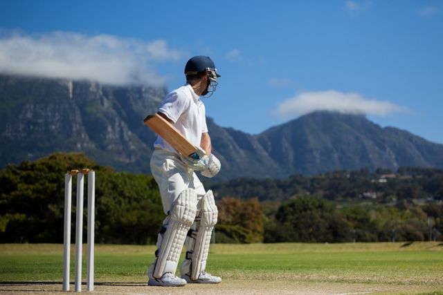Full length of cricket player practicing against blue sky on field