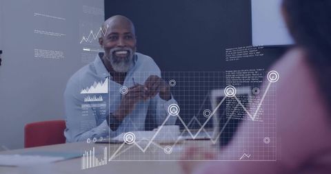 Senior business leader smiling, gesturing and presenting analytics overlay during team meeting