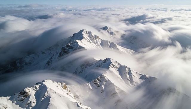 Revealing Central Snow Ridge Rising Through Swirling Clouds Over Jagged Alpine Peaks