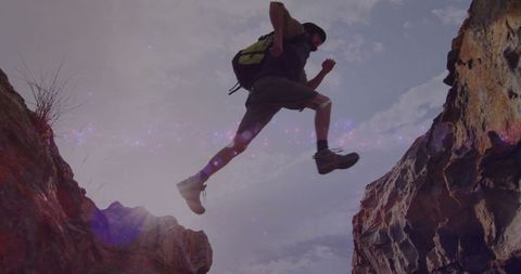 Adventurous Hiker Leaping Across Canyon Gap in Wilderness