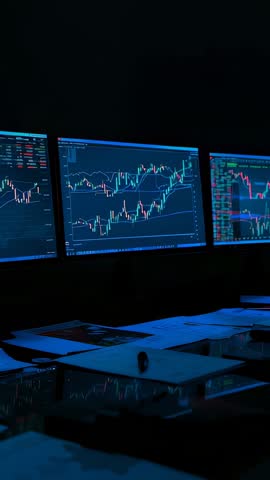 Vertical video streaming market data across multi-monitor trading desk with live candlestick charts