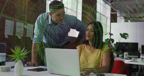 Male Mentor Guiding Female Colleague Collaborating at Laptop in Modern Open-Plan Office