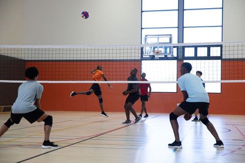 Teenage male players spiking volleyball in indoor gymnasium during fast-paced youth match