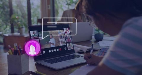 Schoolchild Taking Notes During Live Online Class at Home Desk with Laptop and Books