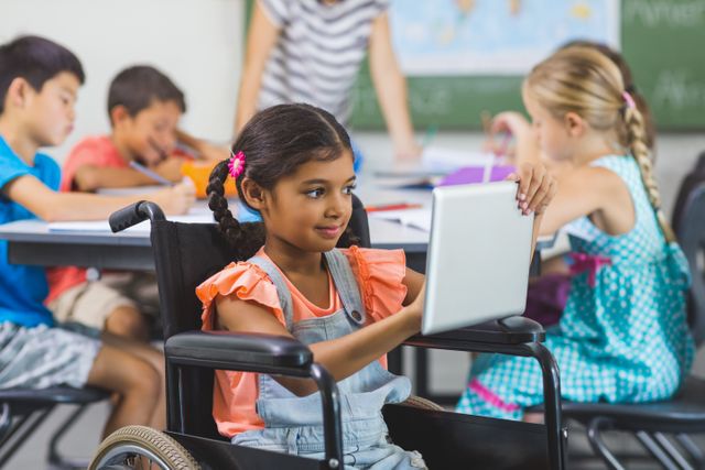 Disabled schoolgirl using digital tablet in classroom at school