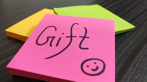 Handwritten gift note on pink sticky note with smiley, bright office post-it stack