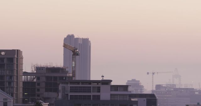 General view of cityscape with multiple buildings, construction site and shipyard covered in fog. skyline and modern industrial urban architecture.