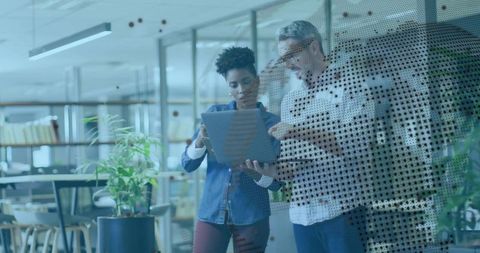 Coworkers collaborating over laptop in modern office space