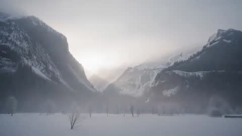 Sunrise Brightening Alpine Valley While Fog Rolls Over Snowy Meadow