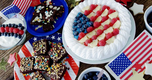 Festive patriotic-themed dessert table featuring a variety of sweets including a cake decorated with berries in the pattern of the American flag, brownies topped with colorful sprinkles and nuts, and other red, white, and blue themed treats. Great for promoting festive holiday gatherings such as Independence Day, Memorial Day, and other U.S. national holidays.