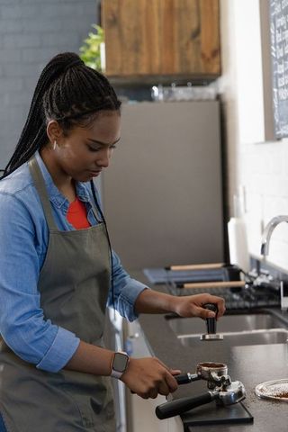 African american barista tamping espresso portafilter at minimalist cafe counter
