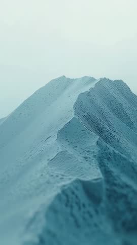 Vertical drone advancing along misty mountain ridge revealing textured blue slopes
