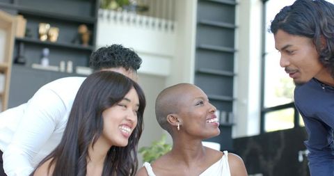 Smiling shaved-head woman connecting with colleagues in bright coworking lounge