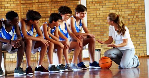 Basketball Coach Encouraging Young Team in School Gym