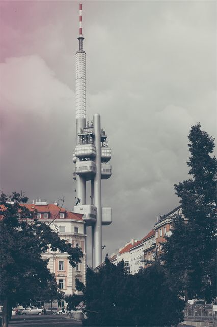 Modern TV tower rising above urban European cityscape with overcast sky. Ideal for representations of telecommunications technology, European travel, and modern architecture.