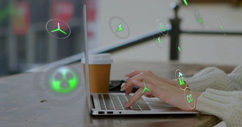 Hands typing on laptop at cafe with green holograms showing sustainability and remote work